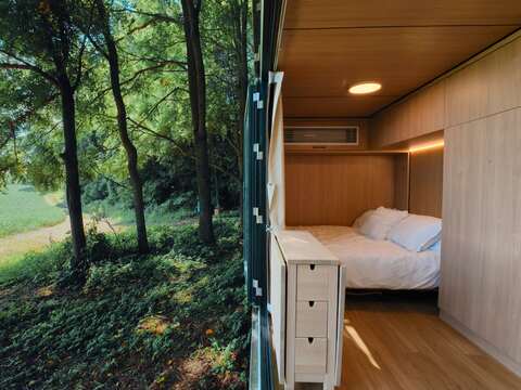 Stainless steel mirror cabin angled among trees